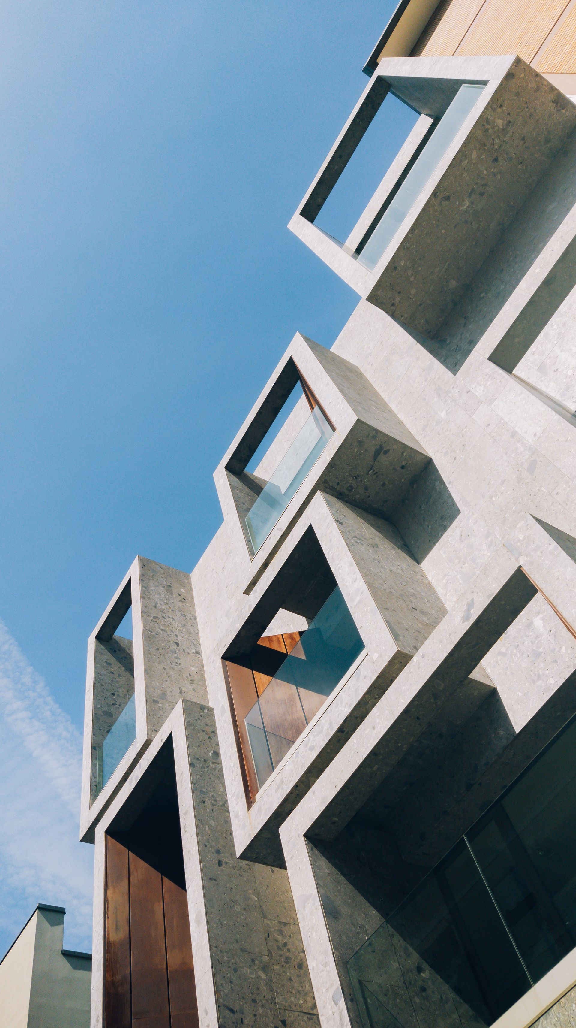 Concrete and glass tower façade in sharp daylight, seen from below